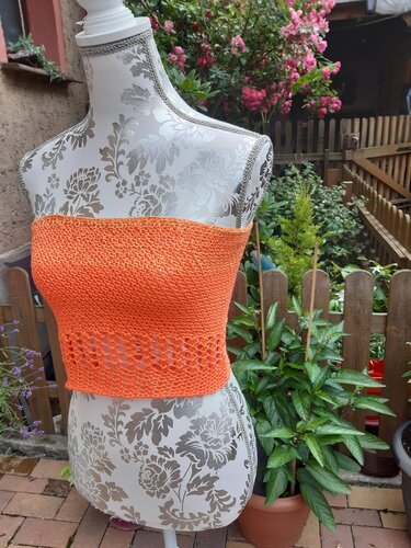 Oranges gehäkeltes Bandeau-Top auf Schneiderbüste vor Gartenzaun