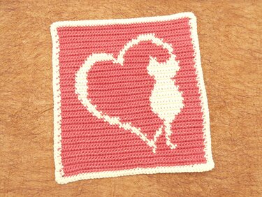 Gehäkeltes Quadrat in Rosa und Creme mit Katzen-Silhouette im Herz