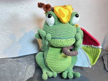 Gehäkelter grüner Amigurumi-Frosch mit gelbem Hütchen und buntem Regenschirm
