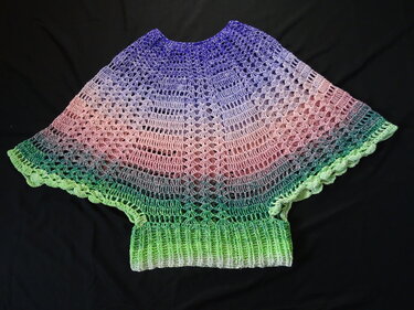 Gehäkelter Poncho in Violett, Rosa und Grün mit geripptem Bündchen auf schwarzem Hintergrund