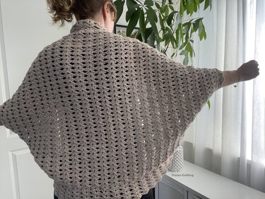 Beiger, gehäkelter Seelenwärmer mit lockerem Muschelmuster, Rückansicht.