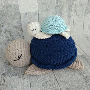 Gehäkelte Amigurumi-Schildkröte in Blau und Beige mit kleinem hellblauem Baby auf dem Panzer