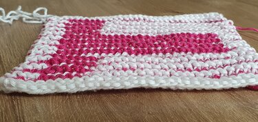 Pink-weißes Bicolor Strickmuster im Kraus‑rechts‑Stich auf Holzhintergrund