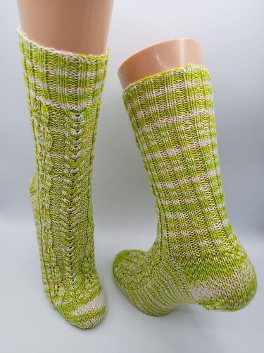 Hellgrün-weiße melierte Stricksocken auf Schaufensterbeinen, mit Zopf-, Rippen- und Ajourmuster