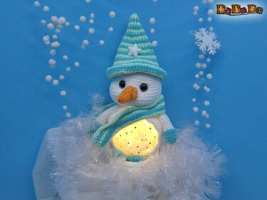 Gehäkelter Schneemann-Amigurumi mit türkis gestreiftem Hut, Schal und leuchtendem Bauch