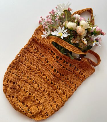 Rust-orange crocheted shopper bag with openwork pattern and flowers inside