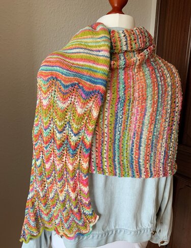 Gestricktes mehrfarbiges Rechtecktuch mit Zickzackmuster auf einer Schaufensterpuppe drapiert.