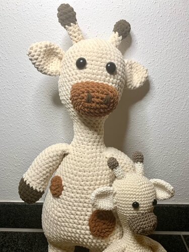 Zwei gehäkelte Giraffen in Creme und Braun vor einer hellen Wand
