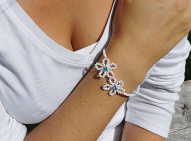Gefädeltes Armband mit weißen Perlen und blauen Mittelperlen am Handgelenk