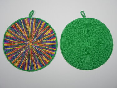 Zwei runde gestrickte Topflappen nebeneinander, links bunt radial gestreift, rechts uni grün, beide mit Aufhängeschlaufe