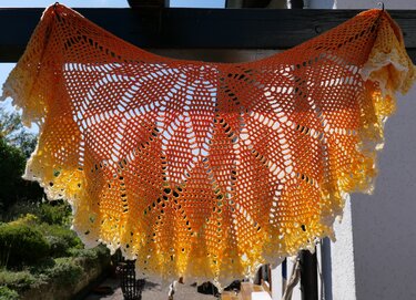 Halbrundes gehäkeltes Tuch mit Blattmuster und Farbverlauf von Orange zu Gelb, gezackte Spitzenkante