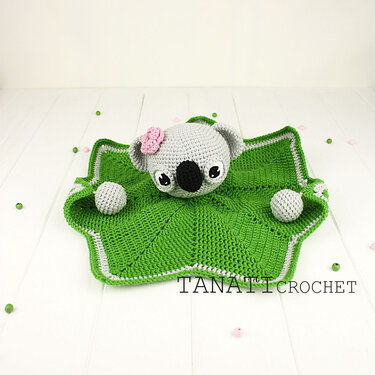 Star-shaped green crocheted baby lovey with gray koala head and pink flower
