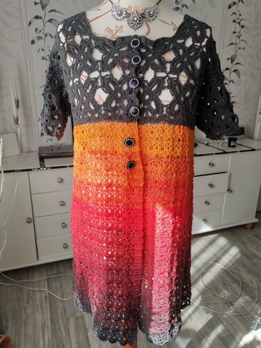 Gehäkelte Kurzarmjacke in Anthrazit, Orange und Rot auf Schneiderpuppe mit sichtbarer Knopfleiste