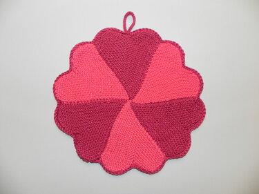 Runder gestrickter Topflappen in Blumenform mit sechs Segmenten in zwei Pinktönen und Aufhängeschlaufe