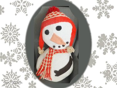 Gehäkelter Schneemann mit rot-weiß gestreifter Mütze, Schal, schwarzen Augen und oranger Nase
