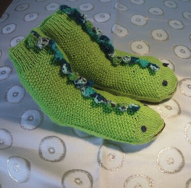 Gestrickte hellgrüne Kindersocken mit Drachenzacken und aufgestickten Augen