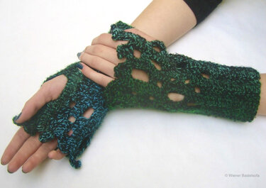Gehäkelte fingerlose Handschuhe in Grün‑Blau mit offenem Lochmuster, getragen