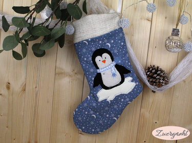 Aufgenähter Pinguin mit Schal als Stickmotiv auf blauem Weihnachtsstrumpf mit Sternenmuster