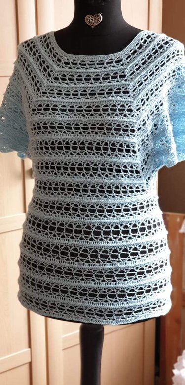Hellblaues gehäkeltes Damen-Shirt mit gestreiftem Lochmuster auf Schneiderpuppe
