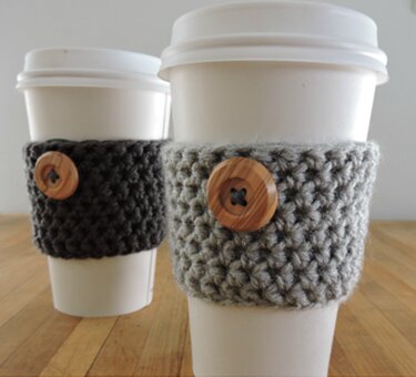 Disposable coffee cups with fast-to-crochet grey sleeves secured by wooden buttons