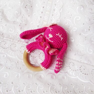 Close-up of crochet rabbit rattle attached to a wooden ring showing stitches and texture