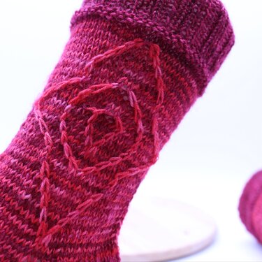 Detailansicht Zopfmuster und geripptes Bündchen einer pink-roten Socke