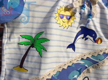 Gestreiftes Kinder‑Shirt mit Plottmotiven: grüne Palme, gelbe Sonne mit Sonnenbrille und blauer Delfin mit Strandball