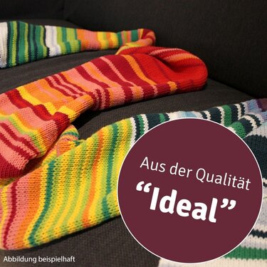 Drei bunte, gestrickte Schals mit Streifen auf dunklem Sofa