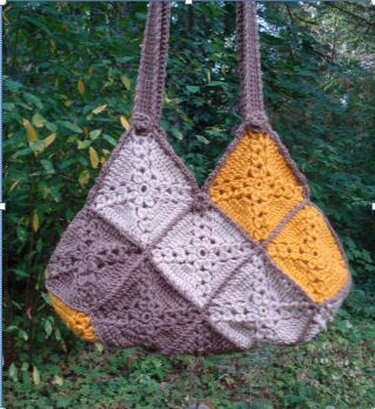 Crocheted granny-square shoulder bag in beige, brown and mustard hanging from a tree branch