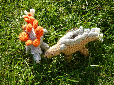 Zwei gehäkelte Dinosaurier-Schlüsselanhänger mit Metallringen auf grünem Gras