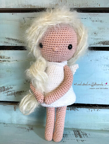 Gehäkelte Amigurumi-Puppe in weißem Kleid mit flauschigem Zopf und dunklen Augen