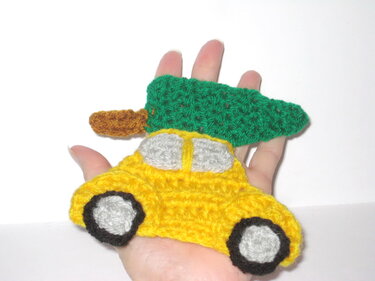 Hand-held yellow crochet car applique topped with a green Christmas tree.