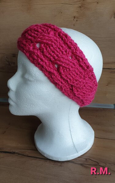 Gehäkeltes pinkes Stirnband mit Zopfmuster auf Modellkopf