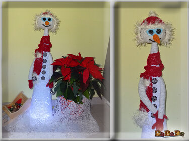 Gehäkelter, beleuchteter Schneemann in Weiß und Rot mit blauen Augen neben Weihnachtsstern (Weihnachtsstern/Poinsettie).