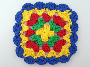 Gehäkeltes buntes Granny-Square in Blau, Gelb, Rot und Grün mit Muschelrand
