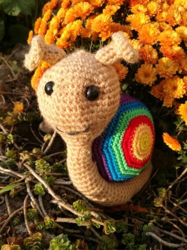 Detailansicht einer gehäkelten Amigurumi-Schnecke mit gestreiftem mehrfarbigem Schneckenhaus