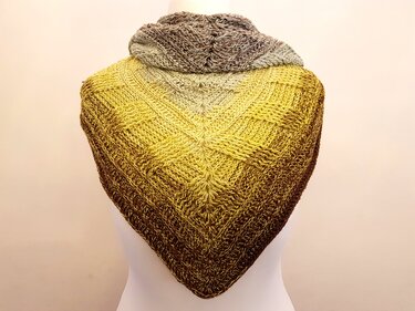 Gehäkeltes Dreieckstuch auf einer Schneiderpuppe, Farbverlauf von Gelb zu Braun, strukturiertes Muster