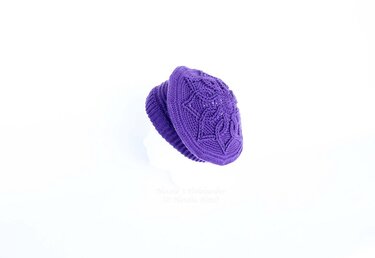Purple crocheted beanie with detailed textured stitch pattern and ribbed edge on a white background.