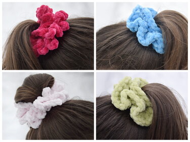Vier flauschige, gehäkelte Scrunchies in Pink, Blau, Rosa und Grün an braunem Haar