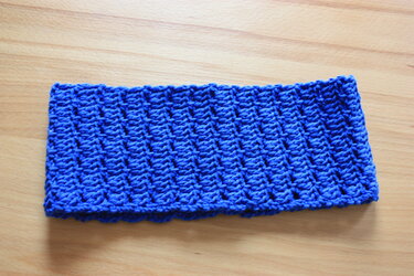 Gehäkeltes blaues Stirnband auf hellem Holzuntergrund