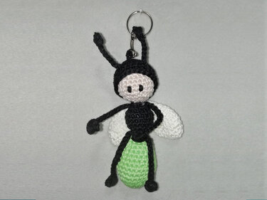 Gehäkeltes Glühwürmchen-Amigurumi in Schwarz, Weiß und Hellgrün an Metallring