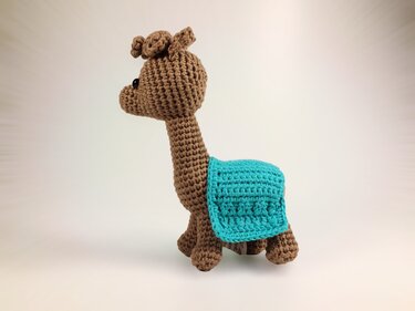 Braunes Amigurumi-Lama mit türkiser Decke, Seitenansicht.