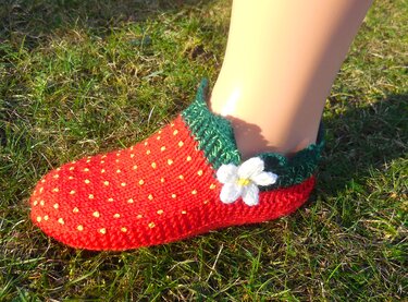 Verspielte rote Kinderhaussocke mit gelben Punkten, grünem Bündchen und gestrickter weißer Blume