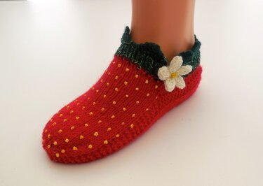 Handgestrickte Erdbeer-Socke in Rot mit gelbem Pünktchenmuster, grünem Bündchen und weißer Blüte