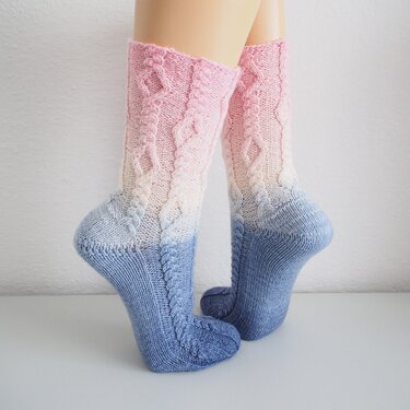 Calf-length knitted socks with pink-to-blue gradient and braided cable stitch