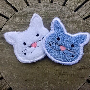 ITH Katzenkopf-Applikationen in Weiß und Hellblau, gestickt, auf Holzfläche