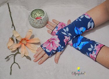 Blaue, fingerlose Armstulpen mit rosa Blumen und Kolibri-Motiv an den Händen