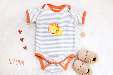 Gestreifter Kurzarm-Body mit orangefarbenen Bündchen und Löwen-Applikation auf hellem Fell, neben gestrickten Babyschuhen und Herzknöpfen