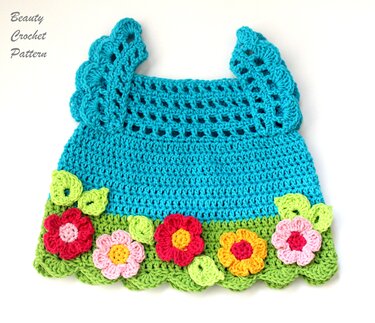 Türkis gehäkeltes Babyträgerkleid mit grüner Muschelbordüre und bunten Blumen