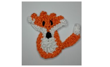 Gehäkelte Fuchs-Applikation in Orange und Weiß auf weißem Hintergrund